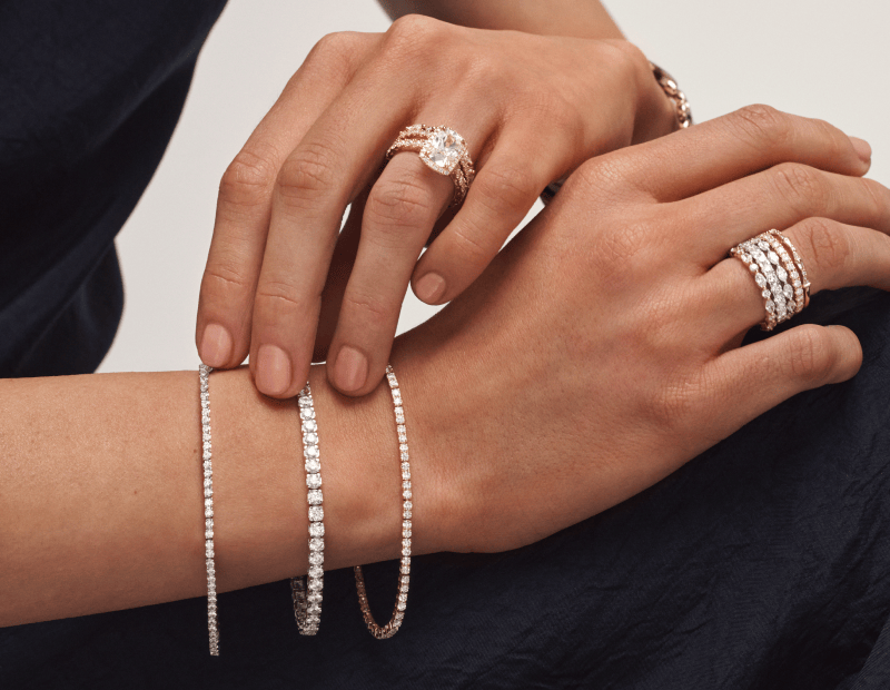 Modal wearing a collection of tennis bracelets, a stack of rings and a wedding set. 