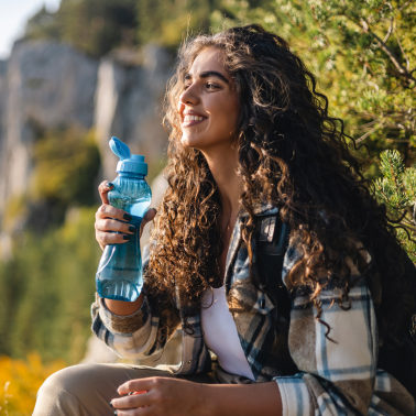 A lady is sitting while holding a bottle of water.
