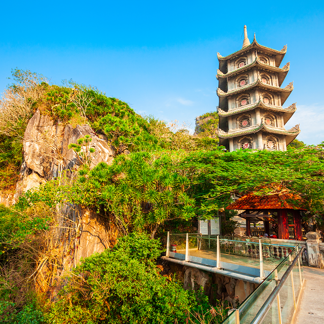 a multi tiered stone pagoda on a lush green hill