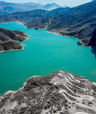 An aerial view of a vibrant turquoise river winding through a steep, rocky canyon.