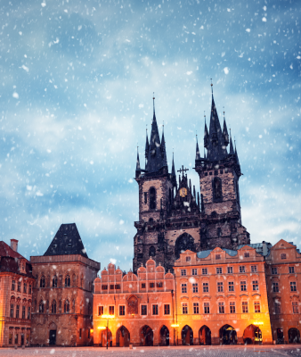 A Gothic church in a city square as snow falls.
