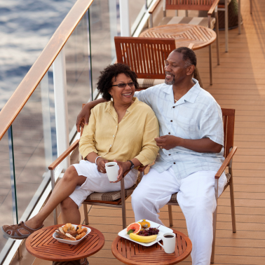 A smiling couple relaxes on the deck of a cruise ship.