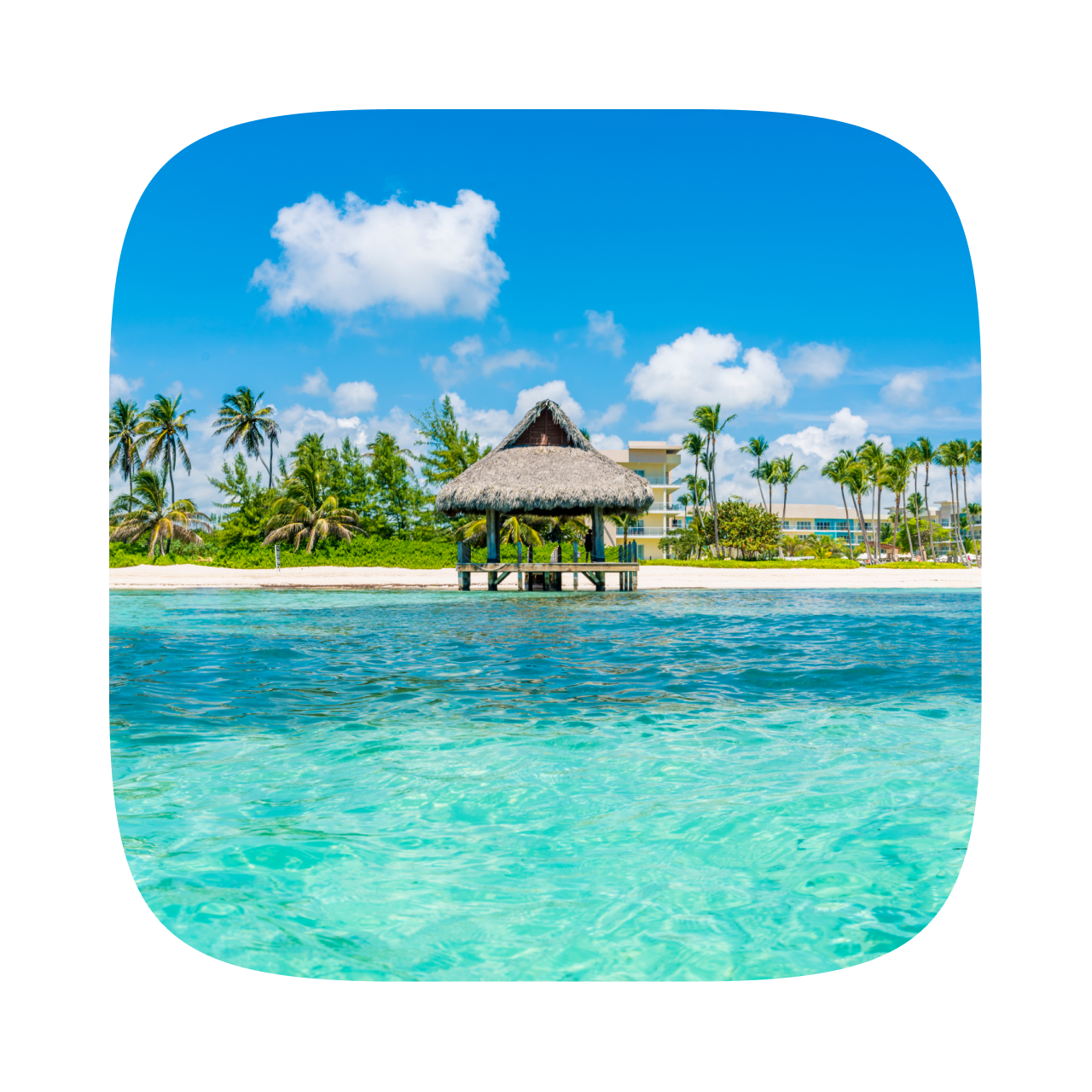 A thatched-roof gazebo sits at the end of a wooden pier over calm, turquoise water.