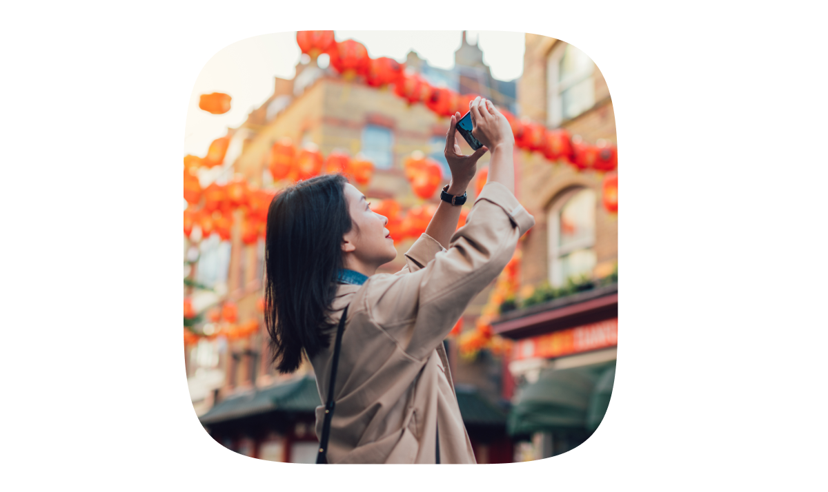 An Asian woman captures the Lunar New Year celebrations with her phone.