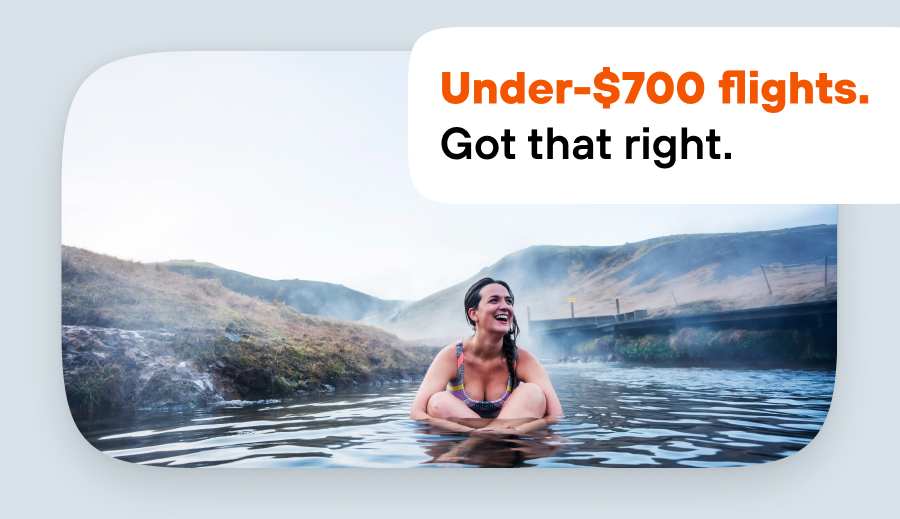 Woman smiling while soaking in a steamy outdoor hot spring.