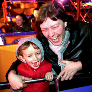 Mom and son laughing together on an amusement ride.