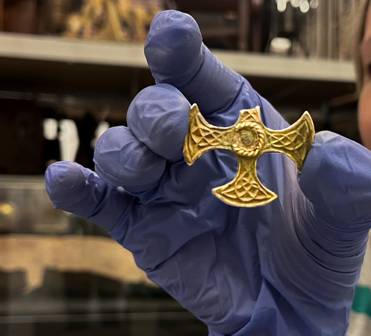 Image of a gloved curator holding the cross up 