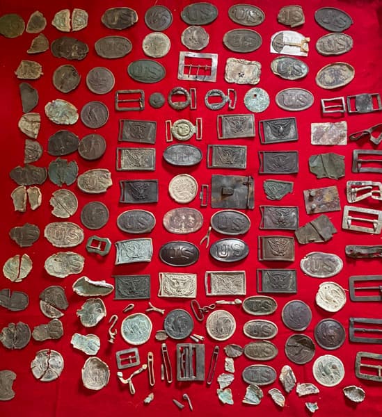 Collection of excavated Civil War belt plates and buckles showing both Union US oval plates and Confederate state plates
