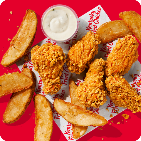 Delicious  wings and wedges on a piece of KFC paper with a sauce.