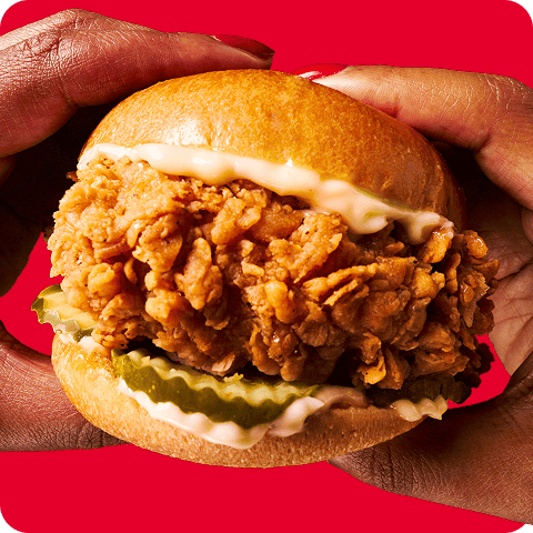 Two hands holding a juicy chicken sandwich.