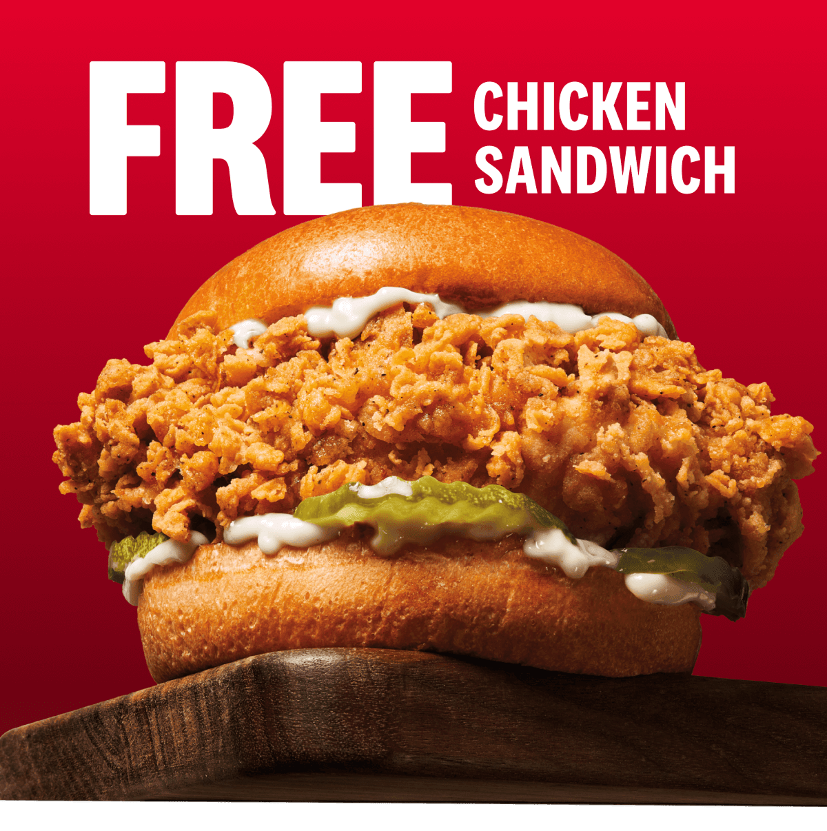 A large chicken sandwich about to fall off a table in front of the words Free Chicken Sandwich