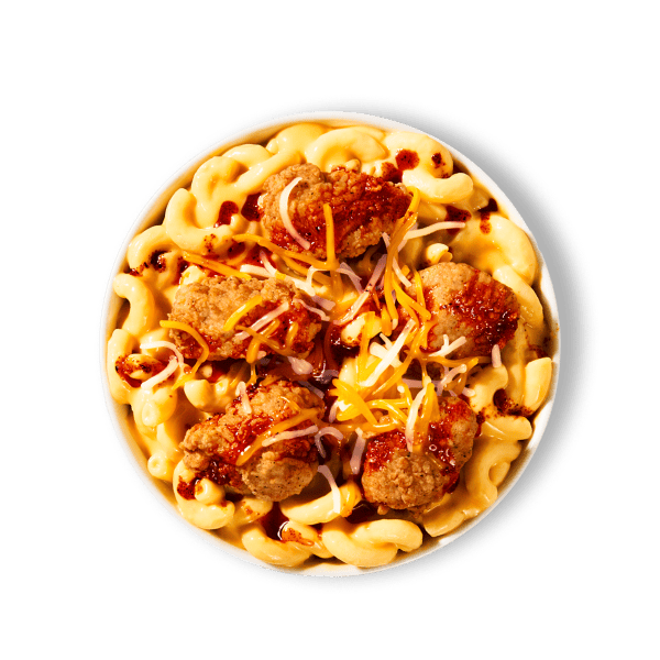 A bowl with creamy macaroni and cheese, crispy popcorn chicken, a three-cheese blend, and Nashville Hot Sauce