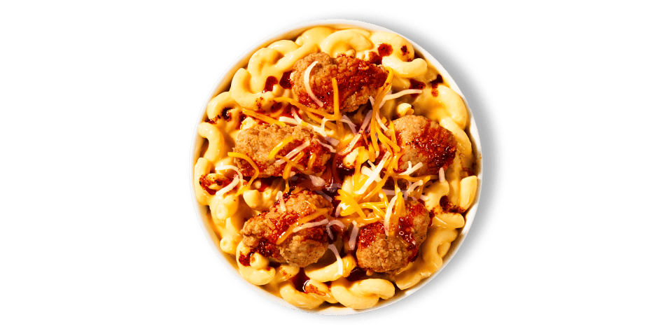 A bowl with creamy macaroni and cheese, crispy popcorn chicken, a three-cheese blend, and Nashville Hot Sauce