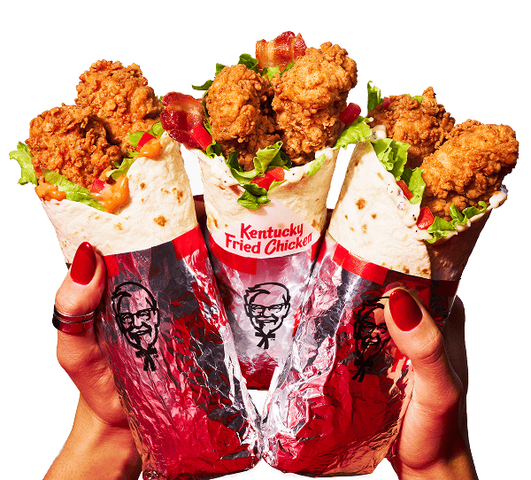 Two hands holding up three KFC Twisters, one Classic, one with Bacon, and one Spicy