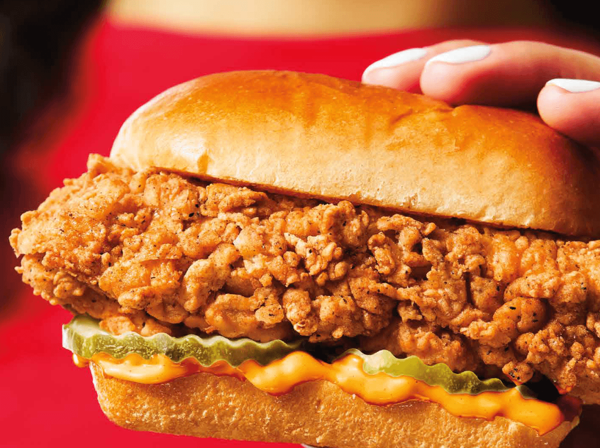 A hand holding a KFC Snacker