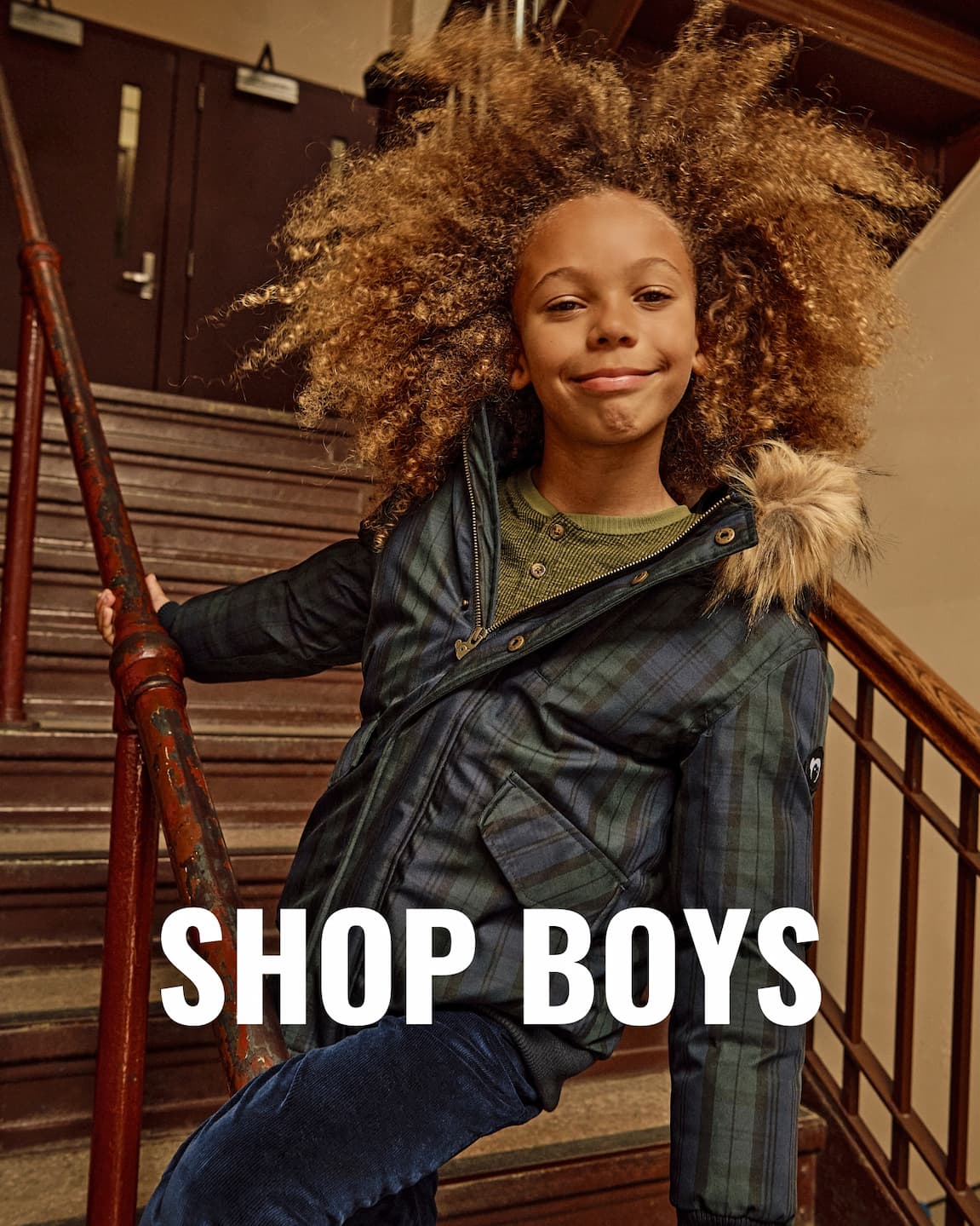 Boys in puffy plaid and green coat with fur hood white text shop boys