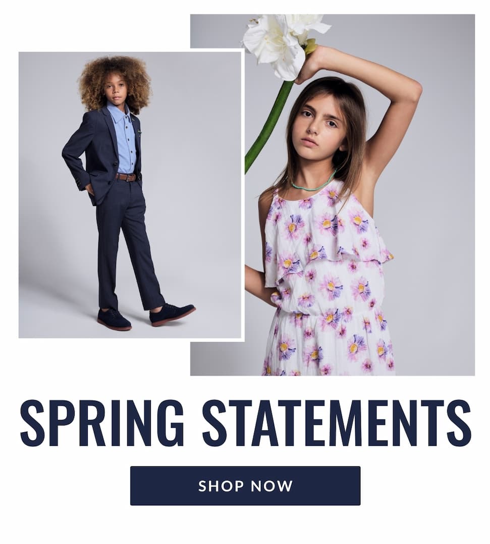 Boy and girl on grey background wearing navy suit and white floral dress