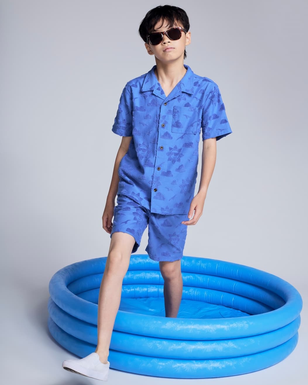 Boy on grey background wearing blue resort set