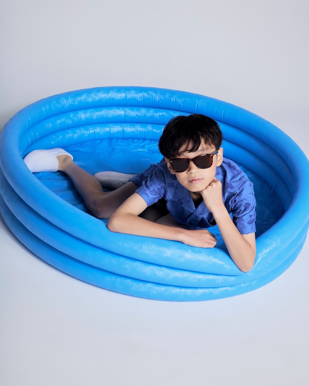 Boy on grey background wearing blue resort set