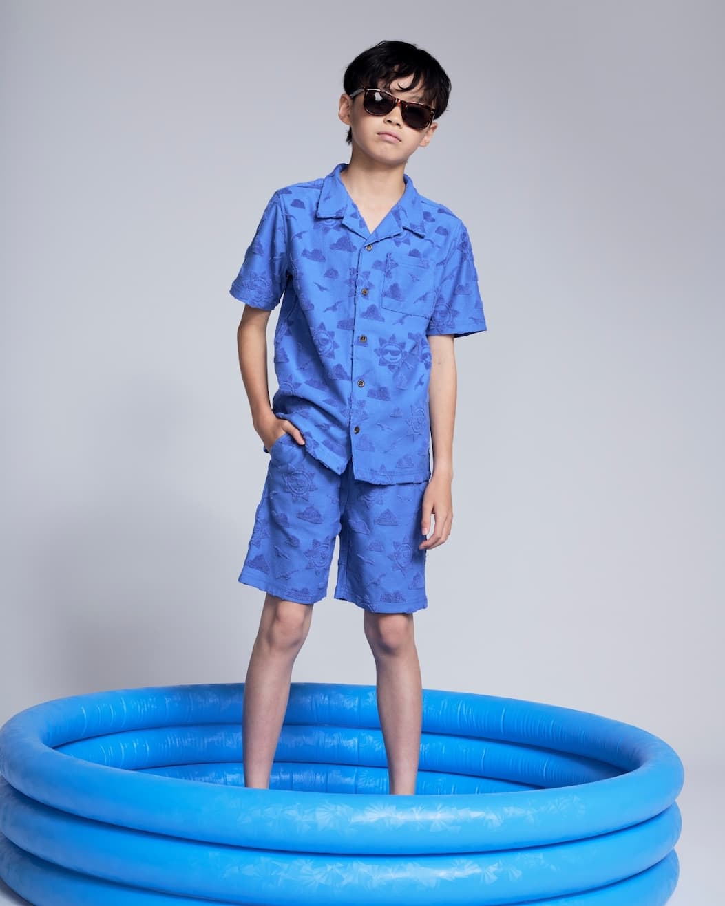 Boy on grey background wearing blue resort set