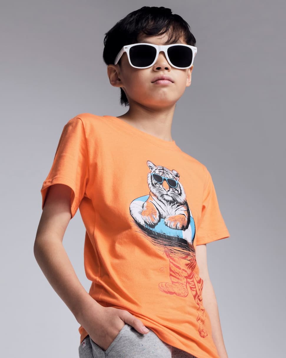 boy wearing orange graphic tee with tiger in pool float