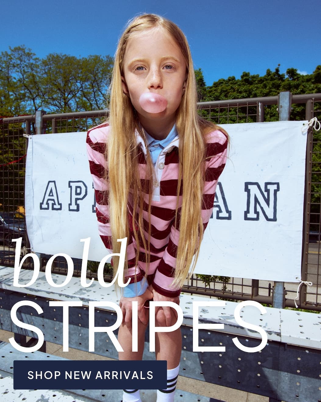 girl wearing pink striped dress outside on bleachers with text bold stripes and shop new arrivals button