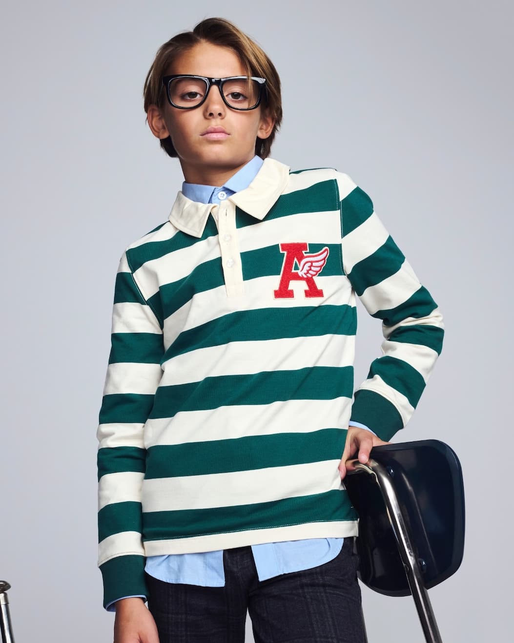 Boy on grey background wearing green and white striped polo