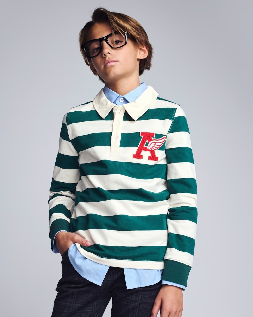 Boy on grey background wearing green and white striped polo