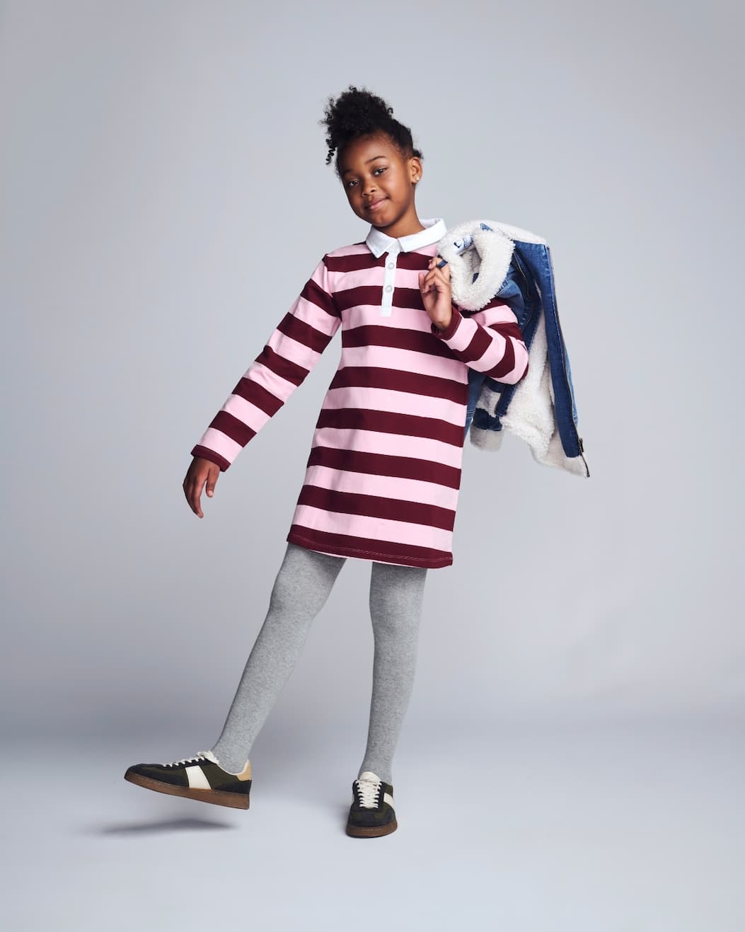 Girl on grey background wearing pink striped long sleeve polo dress 