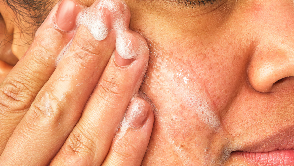 Image of woman washing her face with Aveeno Cleanser wash.