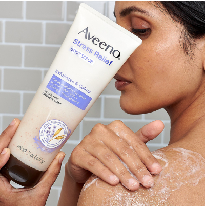 Image of woman applying the Aveeno Stress Relief Body Scrub onto her upper arm.
