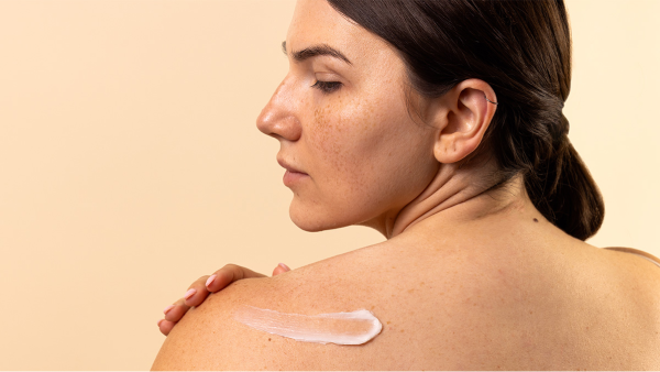 Image of woman puttin Aveeno sunscreen on her shoulder.