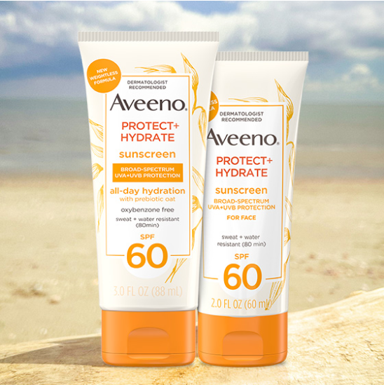 Image of Aveeno Protect and Hydrate Sunscreen bottles in the sand at the beach.