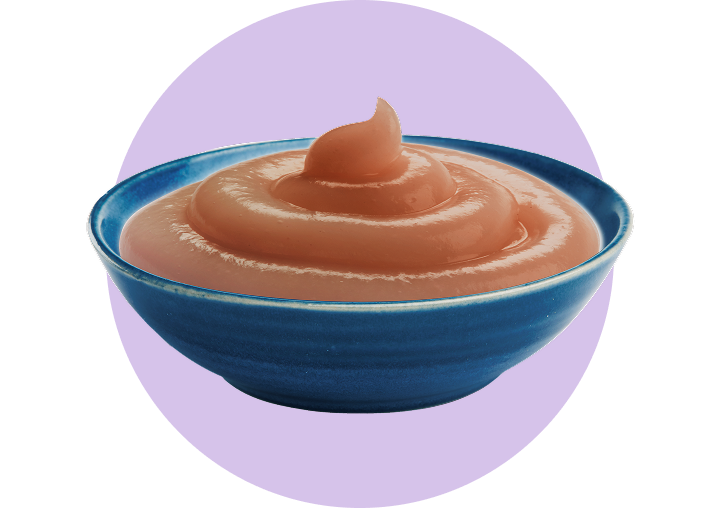 A blue bowl of Tastefuls Purées is next to a sprig of orange flowers.