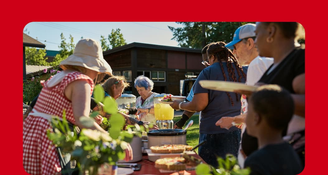 Group of people plating their food at an outdoor potluck