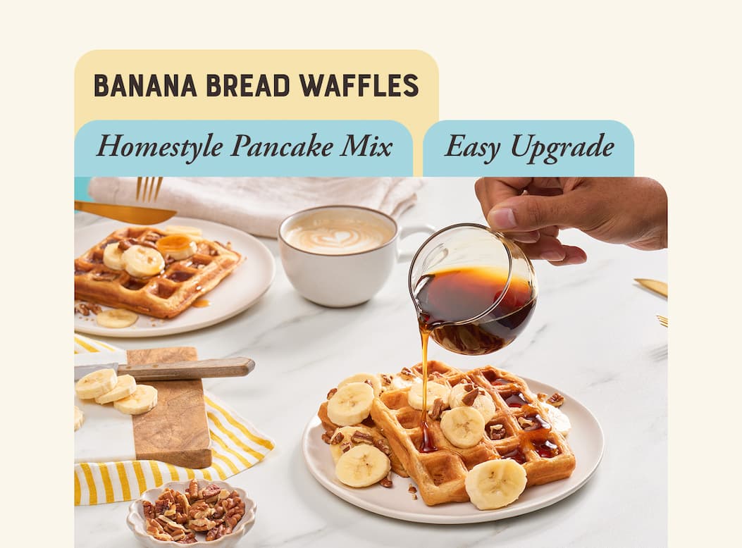 Banana Bread Waffles. Image of golden brown waffles on a plate topped with sliced banana and toasted pecans. Hand drizzling maple syrup on waffles.