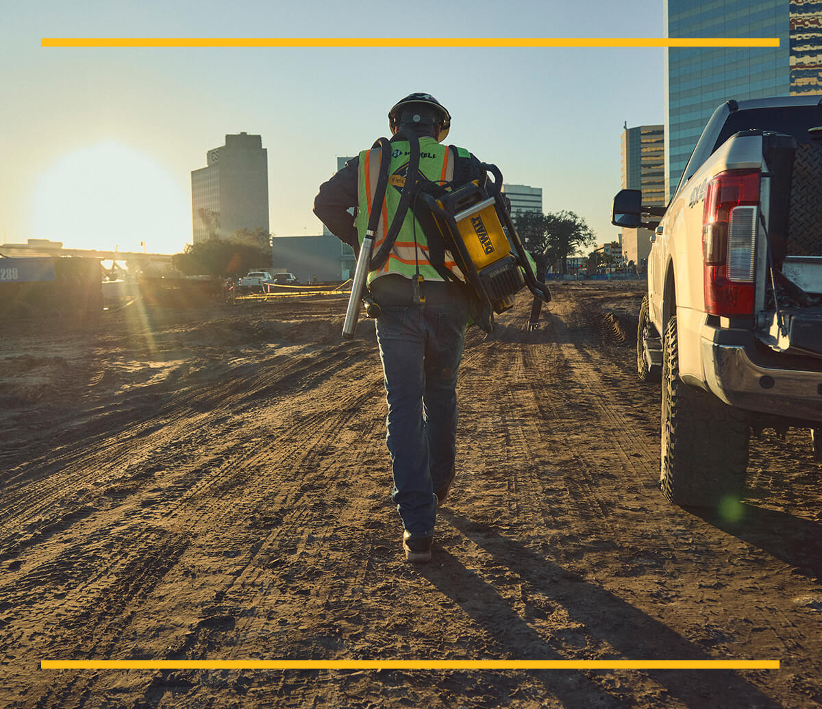 Concrete worker carrying DEWALT POWERSHIFT™ backpack vibrator on jobsite