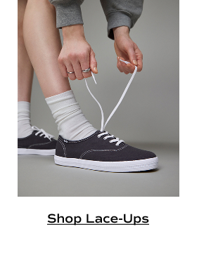 A pair of Keds Champion Canvas Lace-Ups in navy shown on foot paired with off-white socks. Shop lace-ups.