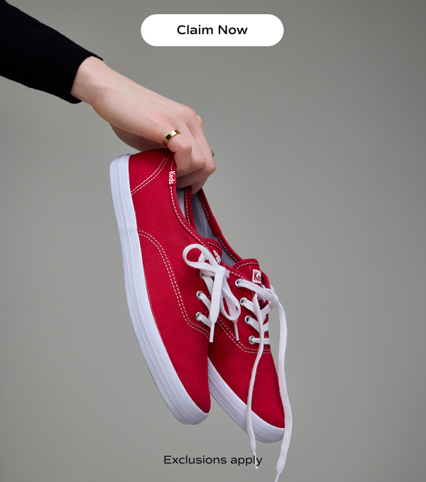 A woman holding a pair of Keds Champion Canvas Lace-Ups in red. Text on the image says Exclusions apply​. Claim Now​.