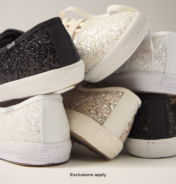 A grey background with a pile of the brilliant Keds Champion Glitter Celebrations Lace-Ups in three colors.