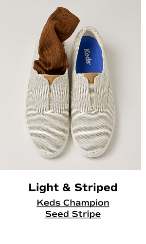 An overhead view of the Keds Champion Round Toe Seed Stripe Slip-On in cream with a brown sock tucked into one of the shoes. The text says Light & Striped. Shop the Keds Champion Seed Stripe.