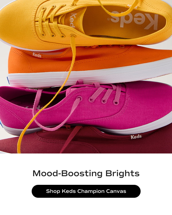 A stack of the Keds Champion Canvas Lace-Ups in dark red, raspberry, orange, and yellow. The text says Mood-Boosting Brights. Shop the Keds Champion Canvas.