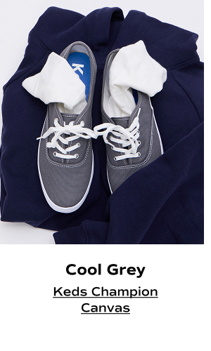 An overhead view of the Keds Champion Original Lace-Ups in graphite grey set on a navy sweatshirt with white socks in each shoe. The text says Cool Grey. Shop the Keds Champion Canvas.