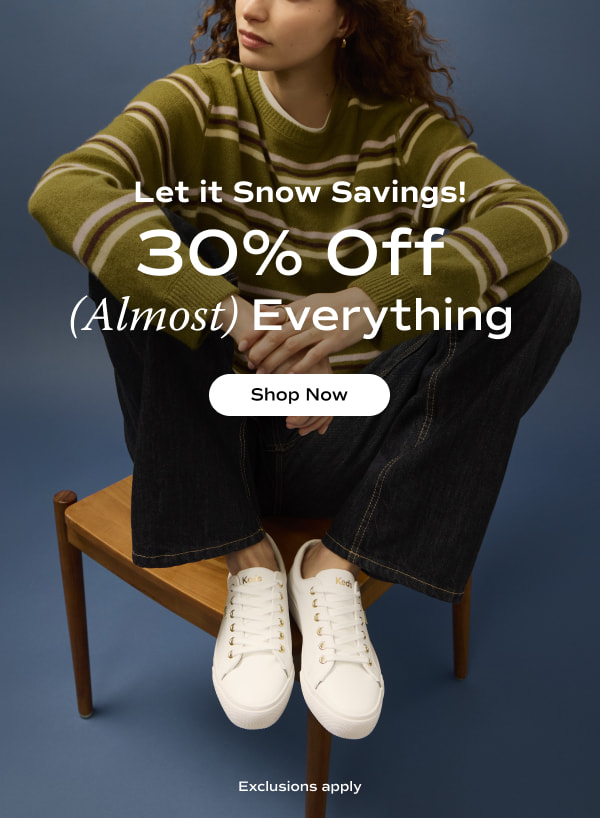 A woman sitting on a chair with her knees up. She's wearing an olive green striped sweater, dark jeans, and the Jump Kick Duo Leather Lace-Up in white/gold. The email says Let it Snow Savings! 30% Off (Almost) Everything. Exclusions apply. Shop Now.