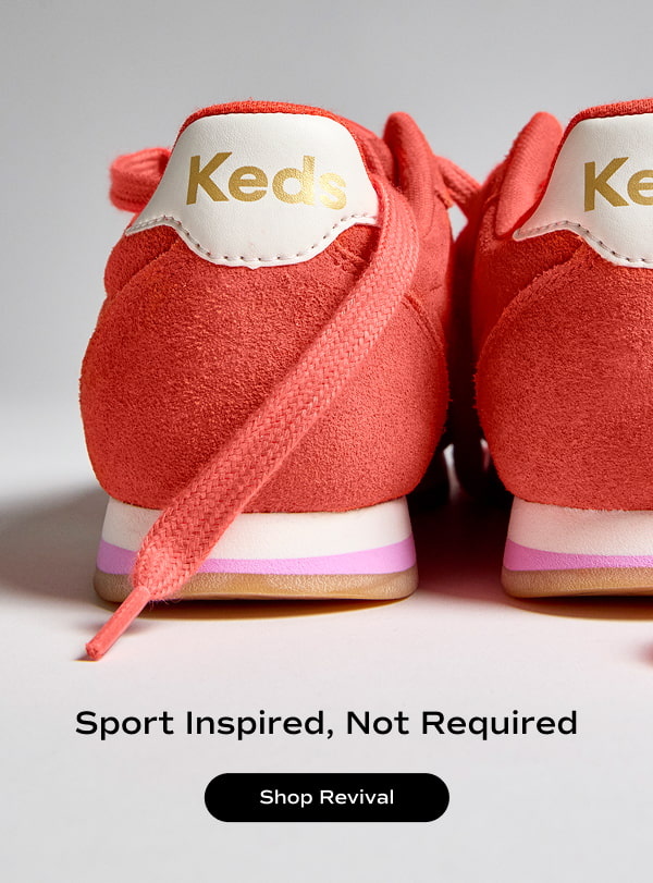 A back view of a pair of Revival Suede Lace-Ups in orange showcasing the gold-and-white Keds heel logo and white outsoles with a pink stripe. Text under the sneakers says Sport Inspired, Not Required. Shop Revival.