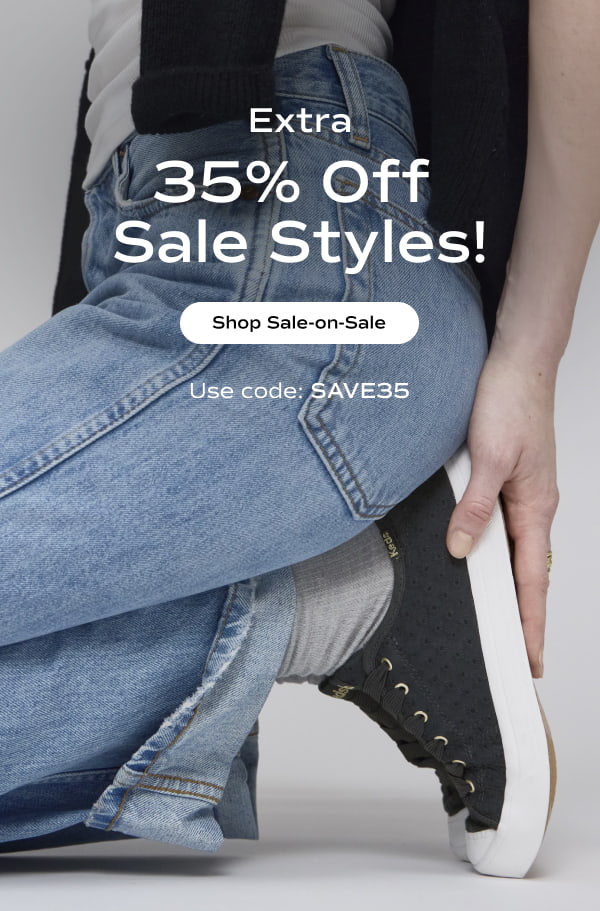 A woman sitting on her heels wearing a white T-shirt, high-waisted light jeans, gray socks, and the Cruise Mini Daisy Eyelet Slip-On in navy. The email says Extra 35% Off Sale Styles! Use code: SAVE35. Shop Sale-on-Sale.