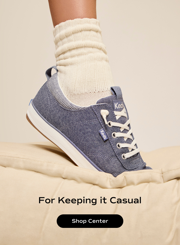 The Center III Chambray Slip-On in blue on foot paired with ribbed socks stepping toe first onto a plush comforter. The text says For Keeping it Casual. Shop Center.