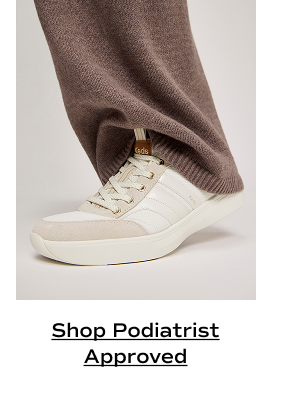 A side view of the BlissWalk Ubal Mesh/Suede/Leather Slip-On in snow white/cognac shown on foot paired with brown knit pants. Shop Podiatrist Approved.