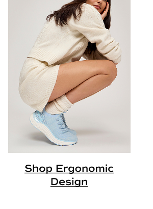 The BlissMove Knit Slip-On in light blue shown on foot paired with scrunched socks and a matching sweater-and-shorts set in cream. The woman is squatting with her heels off the ground in order to demonstrate the sneaker’s flexibility. Shop Ergonomic Design.