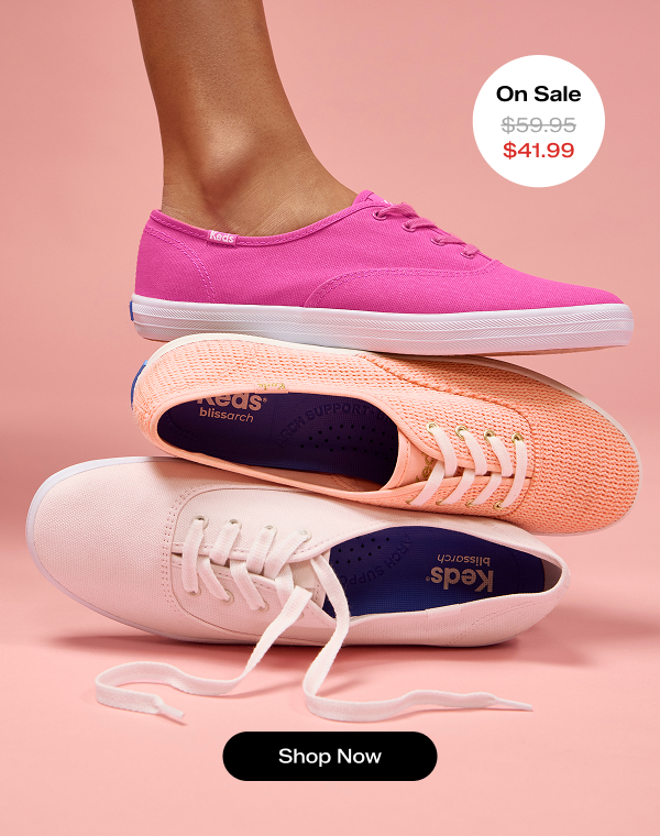 A pink background with a stack of the Keds Champion Lace-Ups in three shades of pink: icy pink, neon coral, and raspberry. The raspberry canvas style on top is on foot. The Keds Champion Canvas Lace-Up or Cotton Mesh Lace-Up was $59.95 and is now on sale for $41.99. Shop Now.